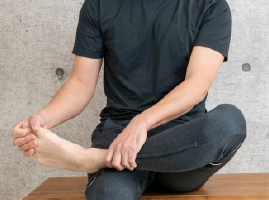 靴を脱いで足を触る男性イメージ